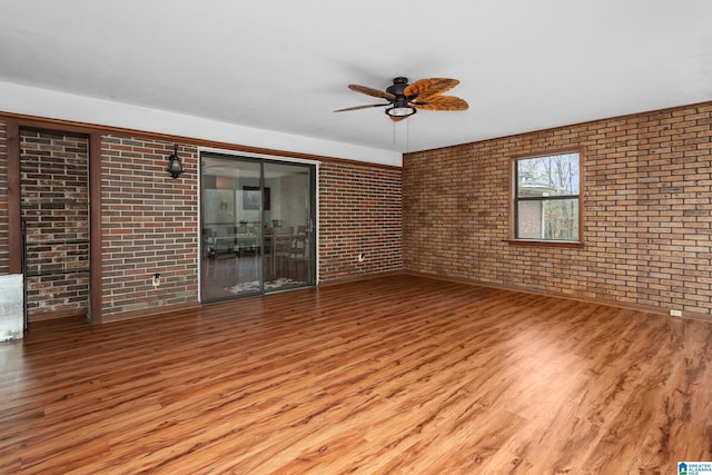 unfurnished living room featuring ceiling fan, light hardwood / wood-style flooring, and brick wall