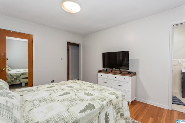 bedroom with light wood-type flooring and ensuite bath