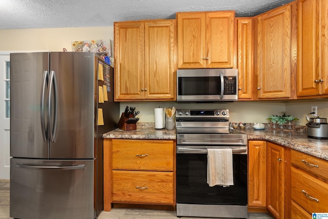 kitchen with dark stone counters, stainless steel appliances, and a textured ceiling