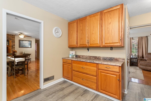 kitchen with ceiling fan, a textured ceiling, and light hardwood / wood-style flooring