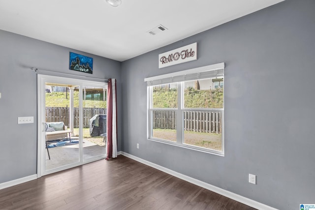 unfurnished room with dark hardwood / wood-style flooring and a healthy amount of sunlight