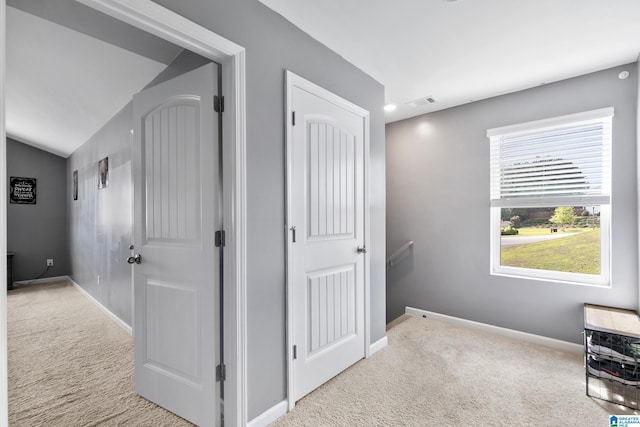 corridor with lofted ceiling and light carpet