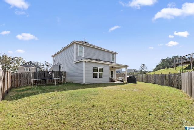 back of house featuring a yard and a trampoline