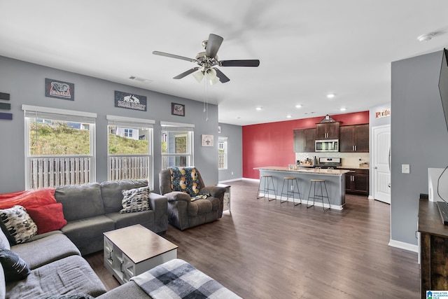 living room with dark hardwood / wood-style flooring and ceiling fan