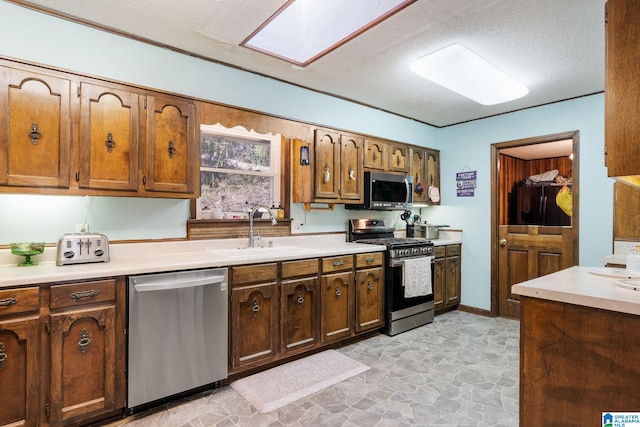 kitchen with a textured ceiling, sink, stainless steel appliances, and a skylight