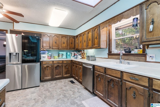 kitchen featuring appliances with stainless steel finishes, a textured ceiling, ceiling fan, and sink