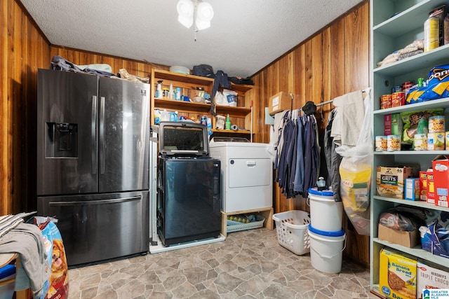 kitchen with a textured ceiling, wood walls, and stainless steel refrigerator with ice dispenser