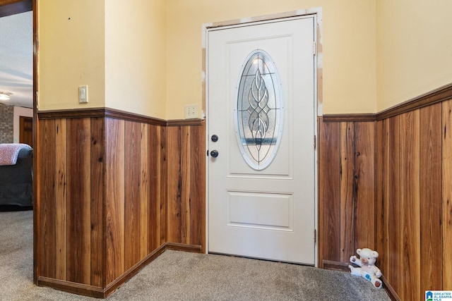 carpeted entrance foyer with wood walls