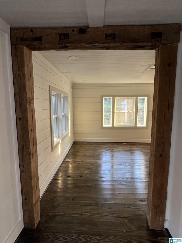 empty room with dark hardwood / wood-style flooring and wood walls