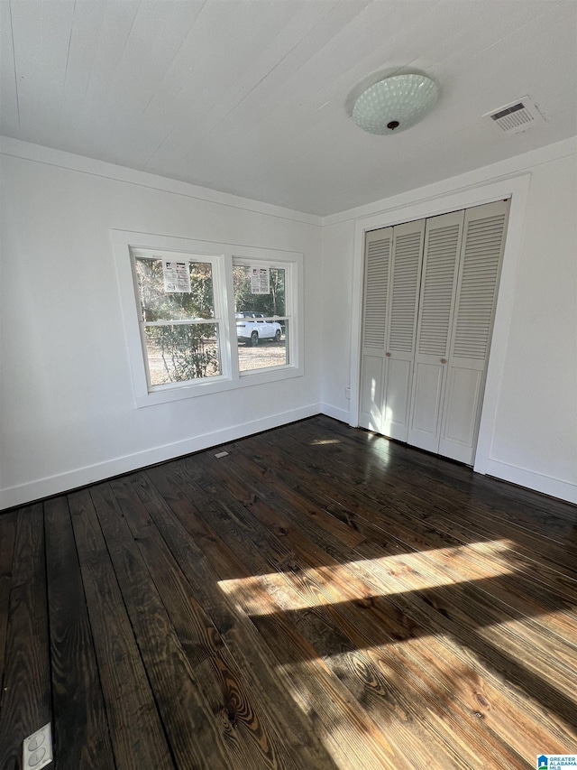 unfurnished bedroom with dark hardwood / wood-style flooring and a closet