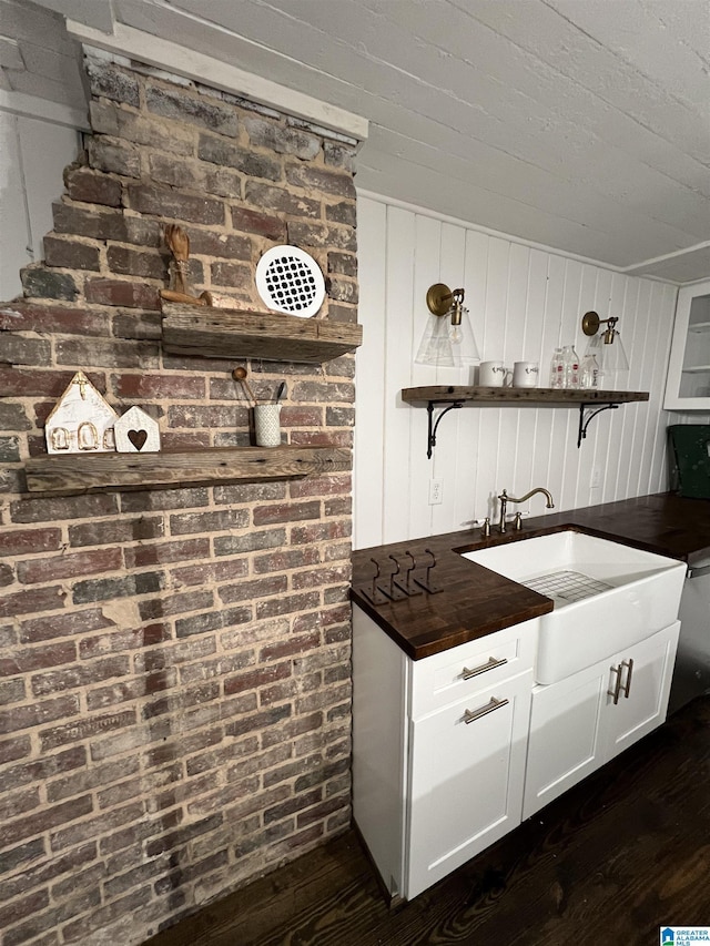 bar with white cabinets, dark hardwood / wood-style floors, sink, and wooden walls