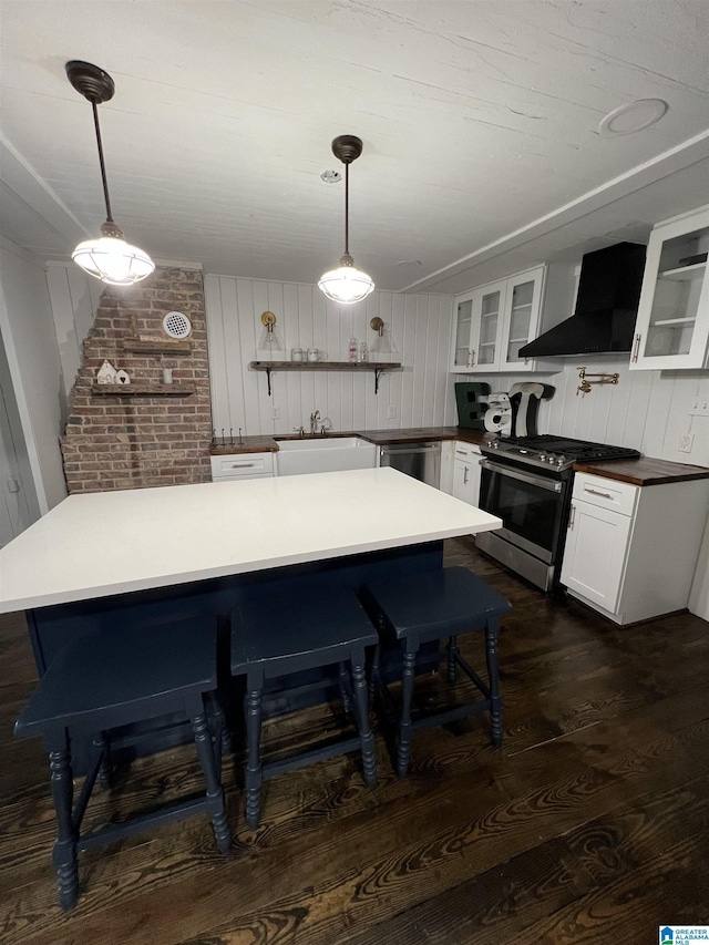 kitchen featuring appliances with stainless steel finishes, wall chimney exhaust hood, decorative light fixtures, and sink