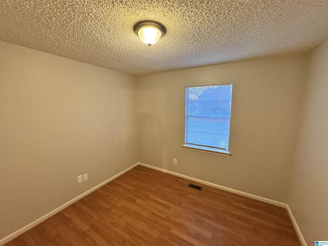 empty room featuring a textured ceiling and hardwood / wood-style flooring