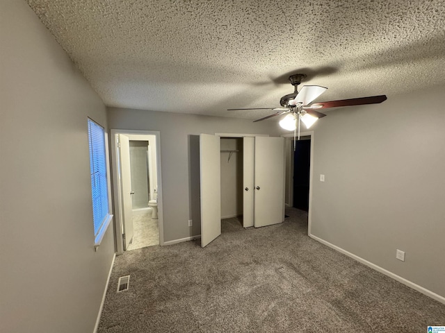 unfurnished bedroom featuring carpet, ceiling fan, a textured ceiling, connected bathroom, and a closet