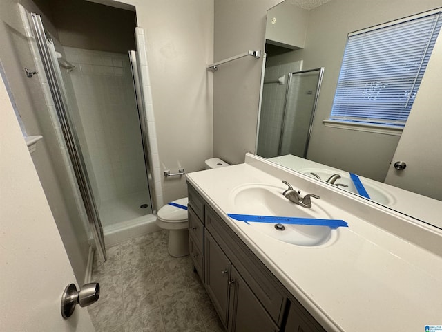 bathroom featuring tile patterned floors, vanity, toilet, and a shower with shower door