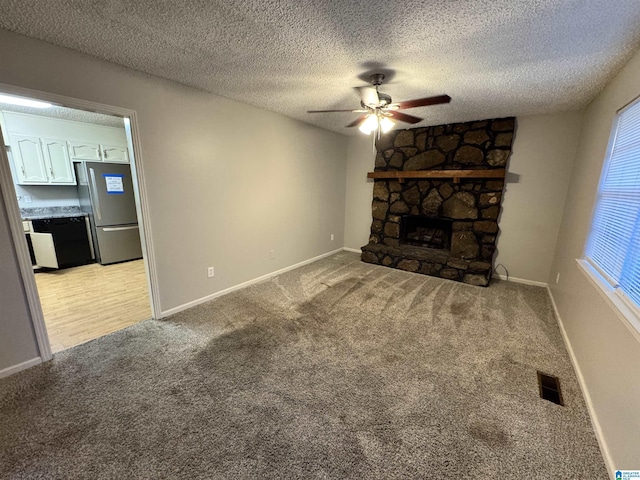 unfurnished living room featuring light carpet, a textured ceiling, a fireplace, and ceiling fan