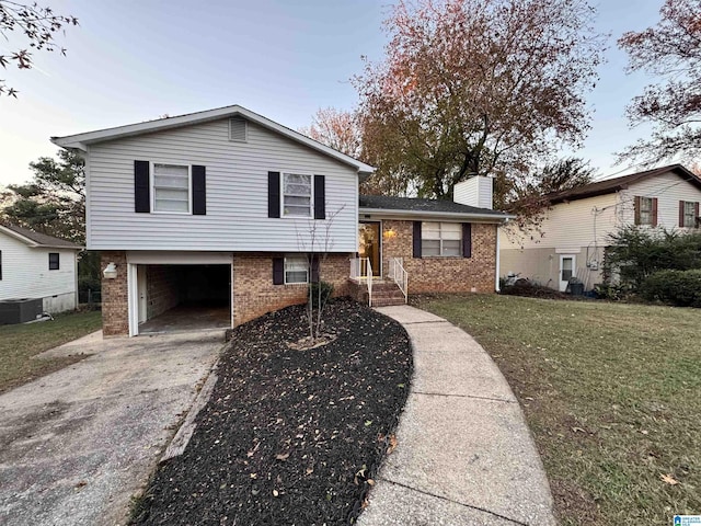 tri-level home featuring a front yard, a garage, and central AC unit