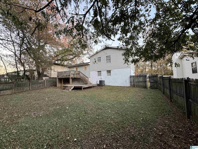 rear view of house featuring central AC unit, a deck, and a yard