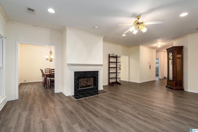 living room with ceiling fan with notable chandelier, dark hardwood / wood-style flooring, a fireplace, and ornamental molding