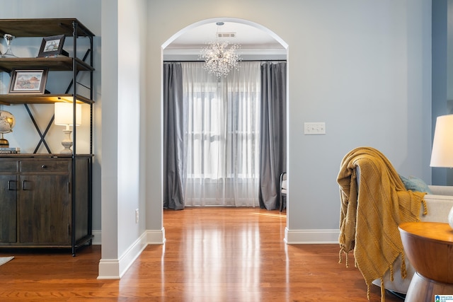 interior space with hardwood / wood-style floors, crown molding, and a notable chandelier