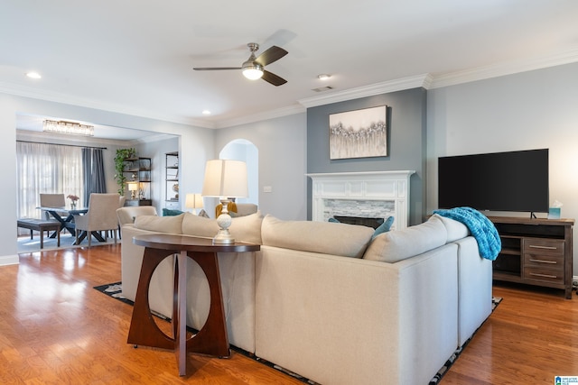 living room featuring a fireplace, hardwood / wood-style flooring, ceiling fan, and crown molding