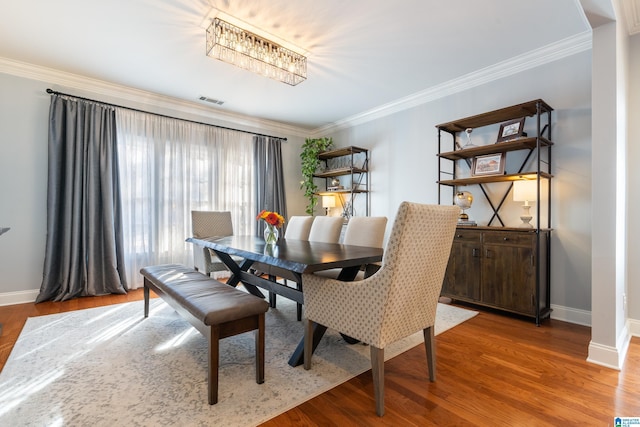 dining area with hardwood / wood-style flooring and crown molding