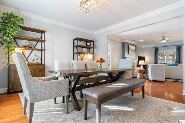 dining space featuring ornamental molding, ceiling fan with notable chandelier, and light wood-type flooring