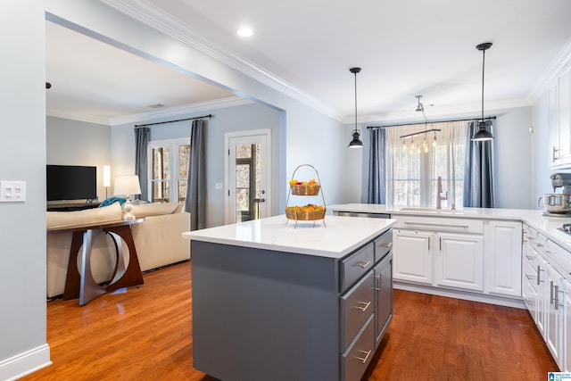 kitchen featuring sink, decorative light fixtures, white cabinets, a center island, and dark hardwood / wood-style floors