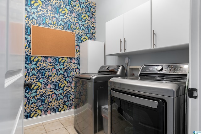 clothes washing area with cabinets, independent washer and dryer, and light tile patterned floors