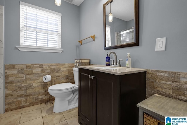 bathroom featuring tile patterned flooring, vanity, tile walls, and toilet