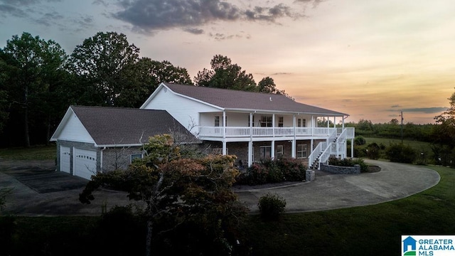 back house at dusk featuring a porch and a garage