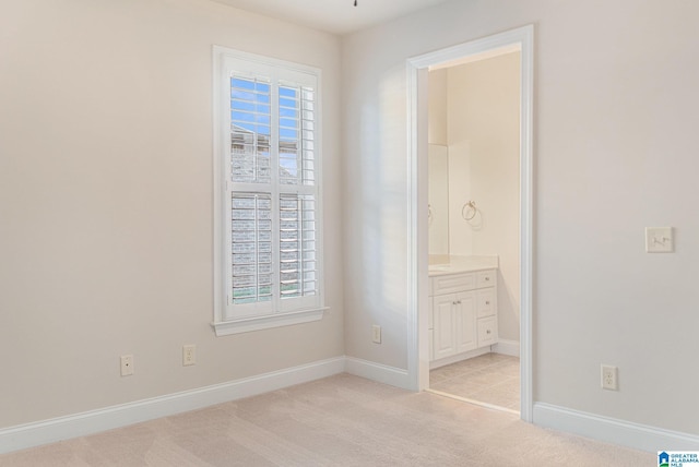 unfurnished bedroom featuring light colored carpet and ensuite bathroom