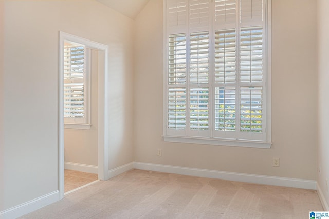 empty room with lofted ceiling and light carpet