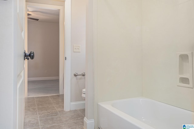 bathroom with tile patterned floors, a tub, and toilet