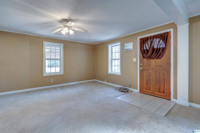 entryway with light carpet, crown molding, ceiling fan, and a healthy amount of sunlight