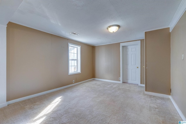 unfurnished room with a textured ceiling, light colored carpet, and crown molding