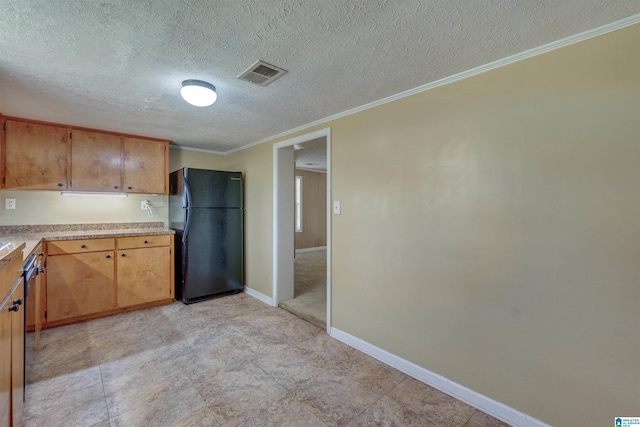 kitchen featuring crown molding, black fridge, and a textured ceiling