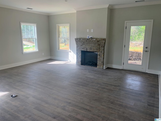 unfurnished living room featuring dark wood-type flooring, a brick fireplace, a healthy amount of sunlight, and crown molding