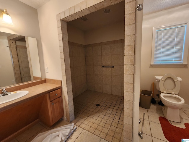 bathroom with tile patterned floors, vanity, a textured ceiling, and tiled shower