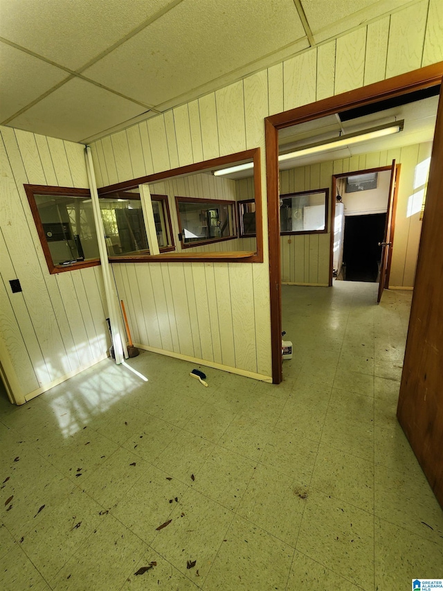 unfurnished room featuring a paneled ceiling and wood walls