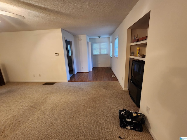 interior space with built in shelves, dark hardwood / wood-style flooring, and a textured ceiling