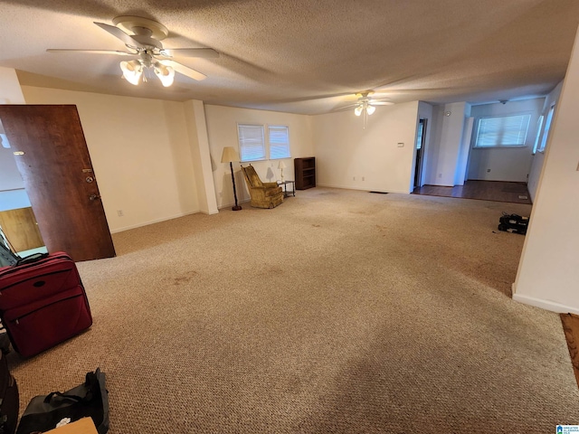 unfurnished living room with ceiling fan, carpet floors, and a textured ceiling