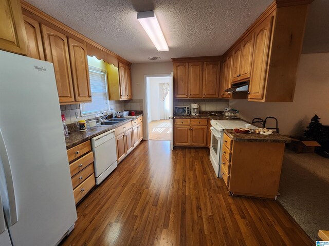 kitchen with dark hardwood / wood-style flooring, backsplash, white appliances, a textured ceiling, and sink