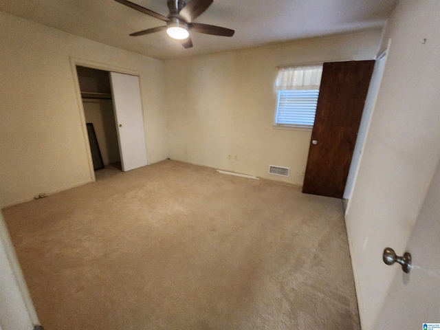 unfurnished bedroom featuring ceiling fan, light colored carpet, and a closet