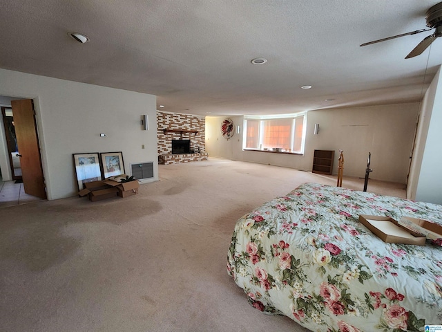 bedroom featuring ceiling fan, light colored carpet, a textured ceiling, and a brick fireplace