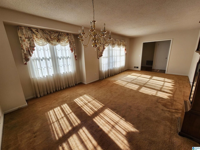 unfurnished dining area with carpet floors, a textured ceiling, and an inviting chandelier