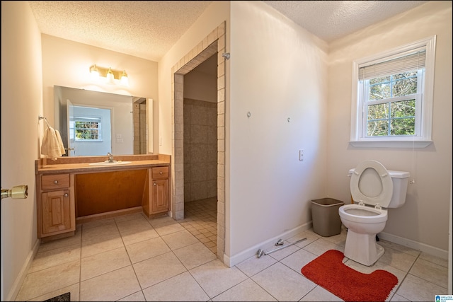 bathroom with tile patterned flooring, vanity, a textured ceiling, and tiled shower