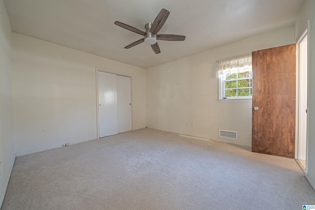 unfurnished bedroom with light carpet, a closet, and ceiling fan