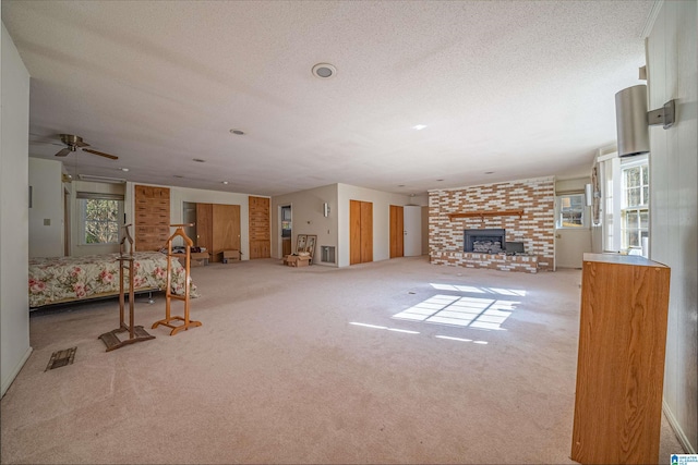 living room with carpet flooring, a textured ceiling, and a brick fireplace