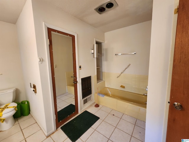 bathroom featuring heating unit, tile patterned flooring, a bathtub, and toilet